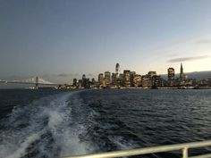 the city skyline as seen from a boat in the water at dusk with lights on