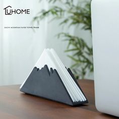 a wooden desk with a laptop on it and some papers in the shape of mountains