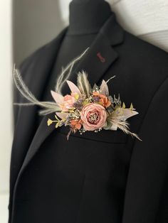 a man in a tuxedo wearing a boutonniere with flowers and feathers