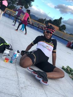 a woman is sitting on the ground with her skateboard and other people in the background