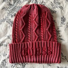 a red knitted hat laying on top of a bed