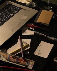 an open laptop computer sitting on top of a desk next to papers and pencils