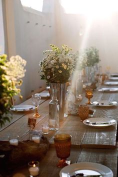 the table is set with plates, silverware and flowers in vases on it