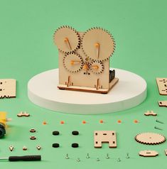 a clock made out of wooden pieces on a green surface with other items around it