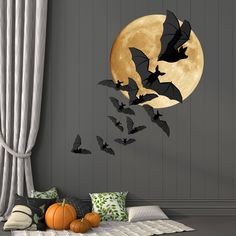 bats flying in front of the full moon with pumpkins on the floor next to it