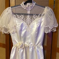 a white wedding dress hanging on a wooden door