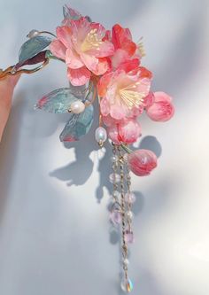 a pink flower brooch with pearls hanging from it's side