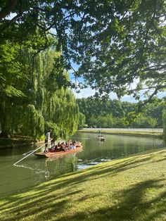 several people are in a boat on the water near some trees and green grass,