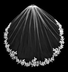 a wedding veil with flowers and leaves on the bottom is seen in this black and white photo