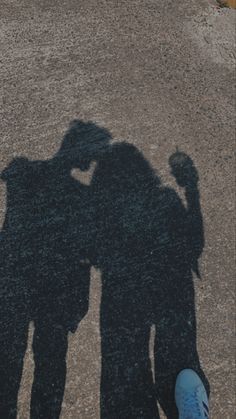 two people standing next to each other with their shadows on the ground and one person's shadow