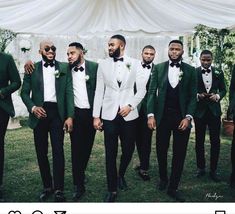 a group of men in tuxedos standing next to each other on the grass