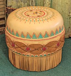 a round wooden box sitting on top of a green floor next to a wooden fence