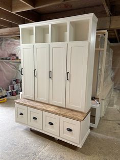 an unfinished room with white cabinets and drawers