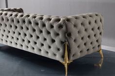 a grey couch with gold legs on a black floor