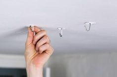 a person is holding their hand up to the ceiling with two hooks on it and one hook in front of them