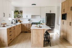 a kitchen with wooden cabinets and white counter tops is pictured in this image, there are two stools at the center of the island