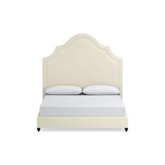 a white bed with an upholstered headboard