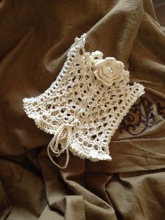 a white crocheted purse sitting on top of a brown cloth covered in fabric