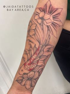 a woman's arm with tattoos on it and flowers in the middle of her arm