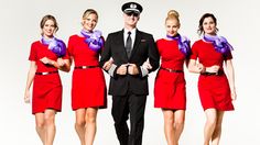 four cabin attendants in red uniforms posing for a photo