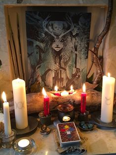 candles are lit in front of a painting and other items on a table with pictures