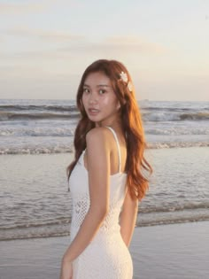 a beautiful young woman standing on top of a beach