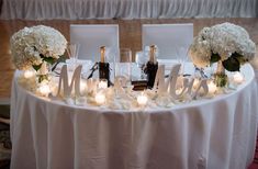 a table topped with white flowers and candles