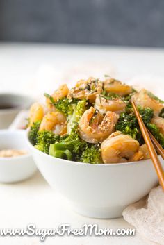 shrimp and broccoli in a white bowl with chopsticks on the side