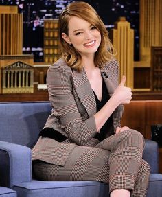 a woman sitting on top of a blue couch in front of a cityscape