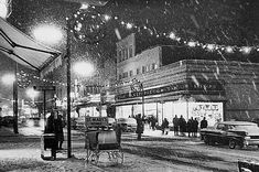 an old black and white photo of people walking in the snow on a city street