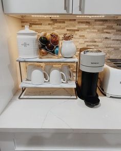 the coffee maker is sitting on top of the counter next to the coffee pot and mugs