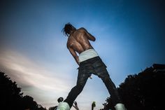 a shirtless skateboarder doing a trick in the air