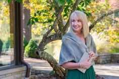 a woman standing in front of a tree with a fur stoler over her shoulders