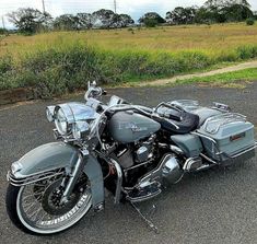 a silver motorcycle parked in a parking lot next to some grass and bushes on the side of the road