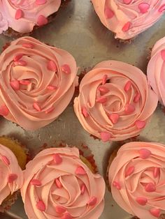 cupcakes with pink frosting and sprinkles arranged on a tray