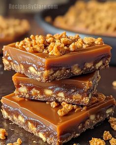 three pieces of chocolate caramel bars stacked on top of each other with walnuts in the background