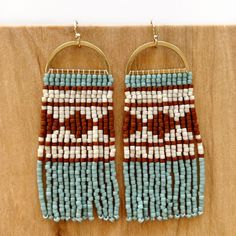 two pairs of beaded earrings on a wooden surface, one is brown and white