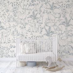 a baby's room with a white crib and wallpaper