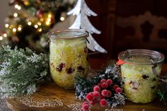 two jars filled with food sitting on top of a wooden table next to a christmas tree