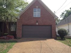 a brick house with two garages in the front yard