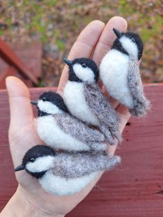 three small birds sitting on top of each other in someone's hand with their fingers