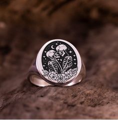 Dive into the enchanting world of romance and mystery with our Skull Lovers Ring, a captivating blend of delicate florals and edgy symbolism. Whether you're searching for the perfect gift for her or him, this Dainty Floral Skull Lovers Signet Ring is sure to delight with its unique charm. For the man who appreciates subtle yet striking accessories, our Skeleton Lovers Pinky Ring is an ideal choice. Crafted with meticulous attention to detail, this ring is a timeless expression of style and indiv Gothic Engraved Rings For Gift, Gothic Rings For Valentine's Day Gift, Valentine's Day Gothic Rings As Gift, Symbolic Rings As Halloween Gifts, Symbolic Rings For Halloween Gift, Silver Spiritual Skull Ring Gift, Spiritual Silver Skull Ring As Gift, Silver Spiritual Skull Ring For Gift, Spiritual Silver Skull Ring For Gift