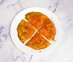 a white plate topped with three pieces of food on top of a marble countertop