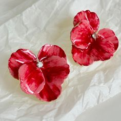 two red flowers sitting on top of a white sheet