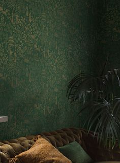 a living room with green wallpaper and a couch in front of a potted plant