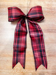 a red and black plaid bow on a wooden surface