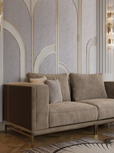 a beige couch sitting in front of a wall with art deco style decor on it