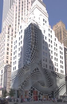 a large building with many windows in the middle of a city street and people walking around it