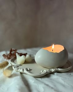 a white candle sitting on top of a plate