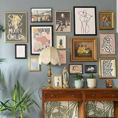 a living room filled with lots of framed pictures on the wall above a wooden table